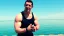 Athletic man in a tank top posing by a lake.
