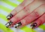 Nail art design featuring black patterns on a gold and silver background.