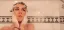 Woman washing her face in the shower.