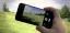 Person holding smartphone to capture landscape photo.