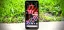 Smartphone displaying a colorful wallpaper on a grassy surface.