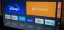 Streaming service icons on a television screen, including Disney+ and Crunchyroll.