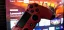 Red PlayStation 4 controller in front of a TV displaying a gaming interface.