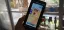 A person holding a smartphone displaying a cartoon game interface.