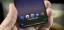 Close-up of a smartphone hand displaying apps with a voice command saying, "Hi, how can I help?"