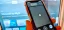 Smartphone displaying a remote control interface in front of a television screen.