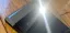Smartphone resting on a wooden surface with sunlight reflection.