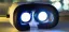 Image of a generic VR headset, with its face side showing, on a table with video playing, which looks like bright white lights where your eyes would go.